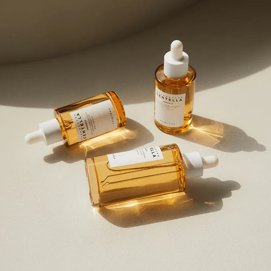 Three bottles of Santella skincare serum on a beige background